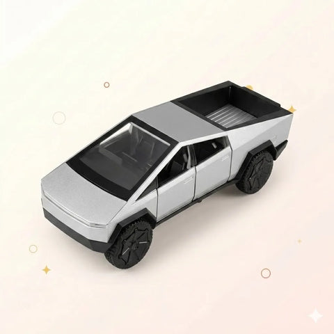 A high-angle view of a silver toy Tesla Cybertruck model, showcasing its unique angular body, open truck bed, and large black rugged tires against a light cream background with gold star and circle accents.