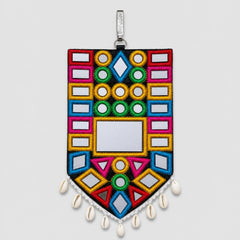 Chowkor Bharat | Option | A colorful South Asian style mirror wall hanging ornament with geometric patterns, white cowrie shells at the bottom, and a silver hanging loop, shown against a neutral gray background.