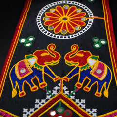 Black | Close-up of a black embroidered textile featuring two stylized elephants in blue, red, yellow, and green, with a large red and yellow floral motif inside a white circular border above.