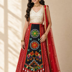 Black | A woman models a traditional Indian ethnic outfit consisting of a red patterned skirt, a cream-colored embroidered blouse, and a red dupatta with gold borders, set against a warm beige background with soft window shadow patterns.