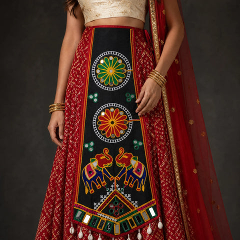 Black | A close-up of a model wearing a traditional Indian red and black lehenga choli with intricate multicolor embroidery, mirror work, and a red dupatta.