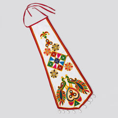 White | A white fabric wall hanging or decorative banner with red trim, colorful folk-art style motifs including flowers, a central geometric diamond pattern, and peacocks, shown on a light gray background.