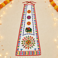 White | A white fabric wall hanging or decorative banner with colorful embroidered patterns, including an elephant motif and floral motifs, displayed flat on a light beige background with decorative string lights and pom-poms around the edges.