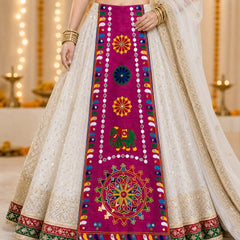 Rani Pink | A close-up of a traditional Indian lehenga choli outfit, featuring a cream-colored embroidered skirt with a prominent magenta center panel decorated with colorful mirror work and embroidery.