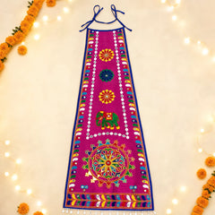 Rani Pink | A bright magenta pink traditional Indian embroidered apron (choli) with blue neck ties, featuring colorful hand-embroidered motifs including an elephant and mandalas, laid flat on a cream background decorated with marigold garlands and fairy lights.