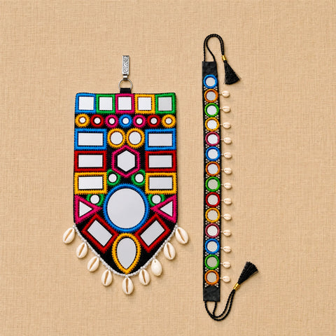 A colorful beaded mirror wall hanging and matching wrist strap set displayed on a beige textured fabric background. The set features geometric patterns with white mirrored squares, colorful bead borders in red, blue, green, yellow, and pink, white cowrie shells, and black tassels.