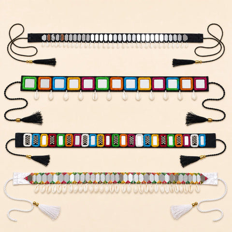 Four beaded waist belts laid flat on a light beige background. The belts feature colorful rectangular bead panels, white hanging beads, tassels, and shell-like embellishments in black, multicolor, and white.